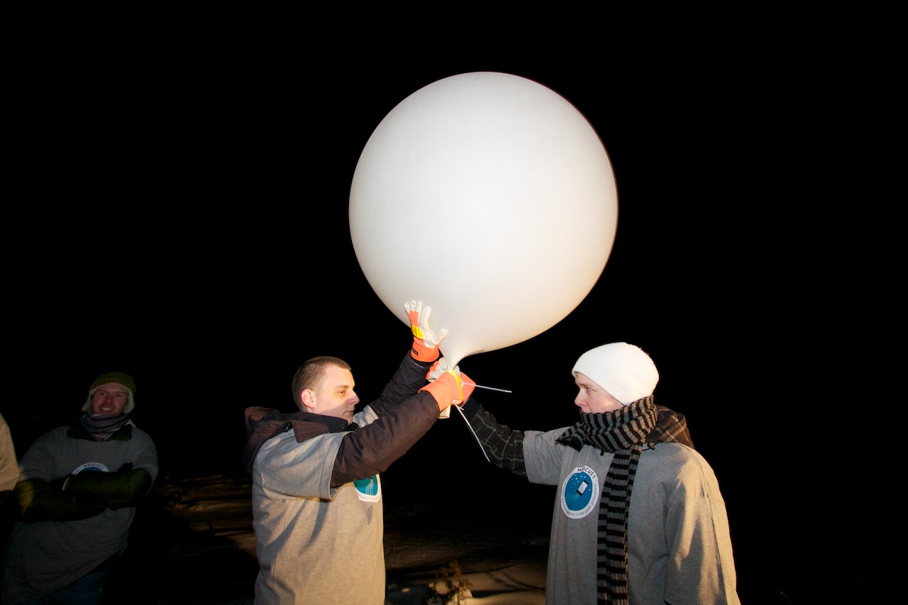 Ready to launch. Simen Andreas Kr Mørch and Morten Grina Myhre are holding the balloon steady while the payload group prepares the mobile phone package and cutdown device.