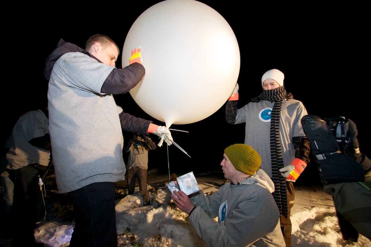 Ready with the timer circuit. Simen Andreas Mørch and Morten Grina Myhre hold the balloon while Daniel Skifjell Larsen sets the counter and closes the box to the cutdown device.
